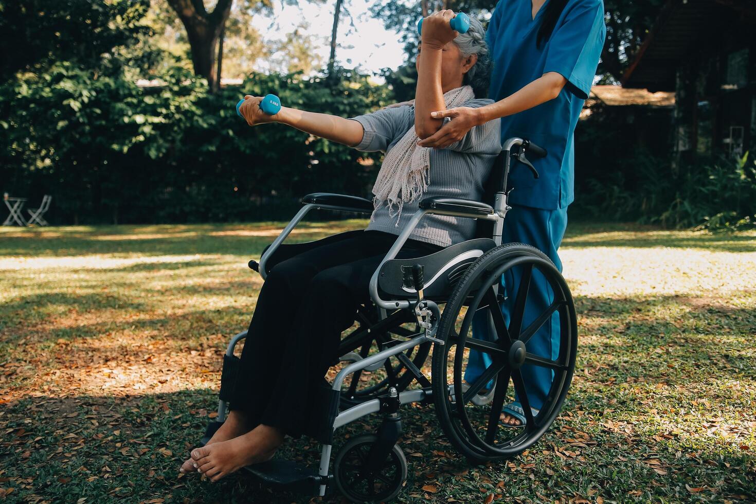 jung Krankenschwester oder Physiotherapeut im Peelings Portion ein glücklich im Ruhestand alt Frau tun Fitness Übungen mit Licht Gewicht Hanteln beim heim. Konzept von Physiotherapie zum Senioren foto