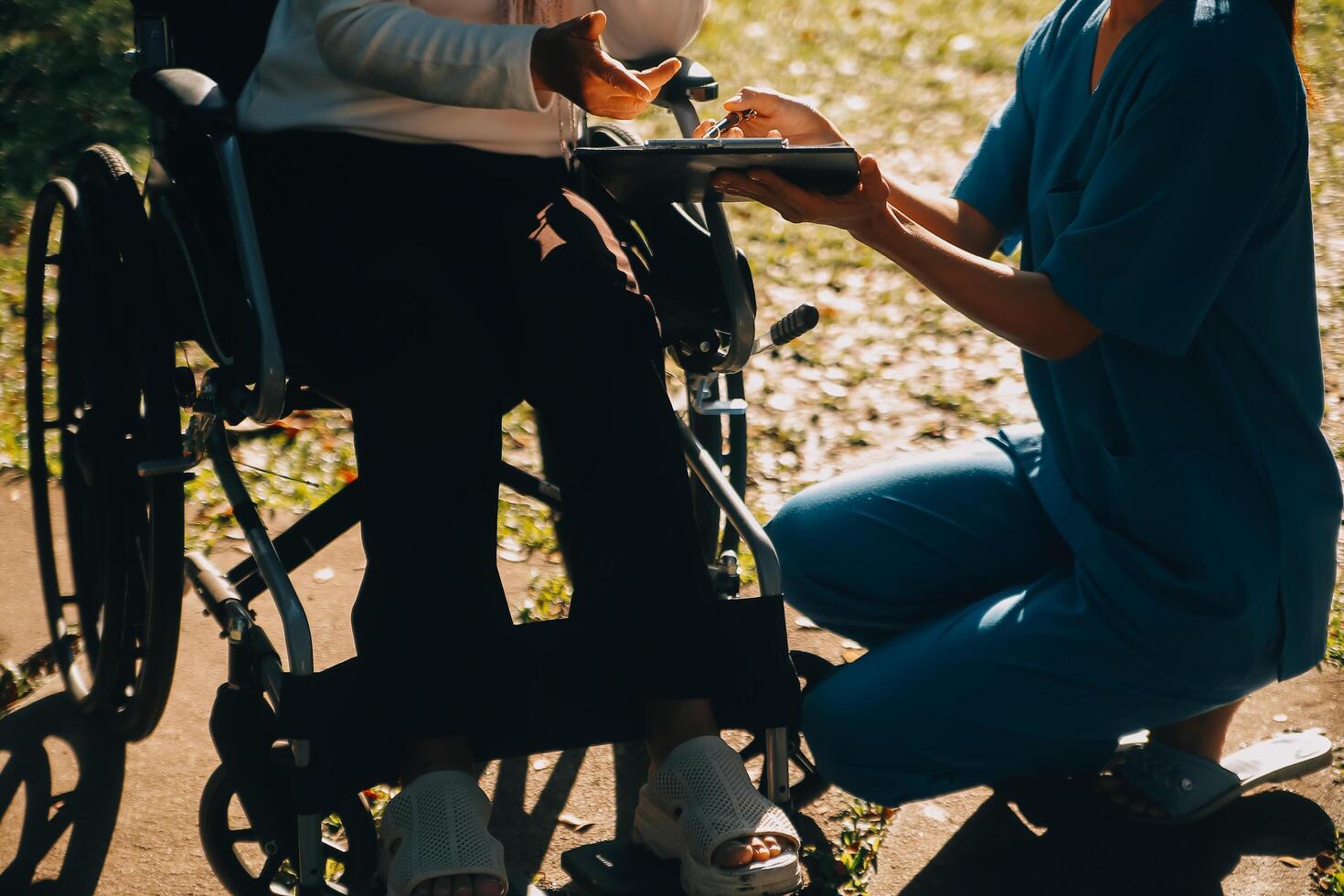 Pflege- Mitarbeiter reden zu ein Alten Person Sitzung im ein Rollstuhl. foto