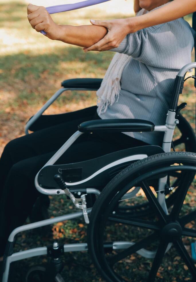 jung Krankenschwester oder Physiotherapeut im Peelings Portion ein glücklich im Ruhestand alt Frau tun Fitness Übungen mit Licht Gewicht Hanteln beim heim. Konzept von Physiotherapie zum Senioren foto