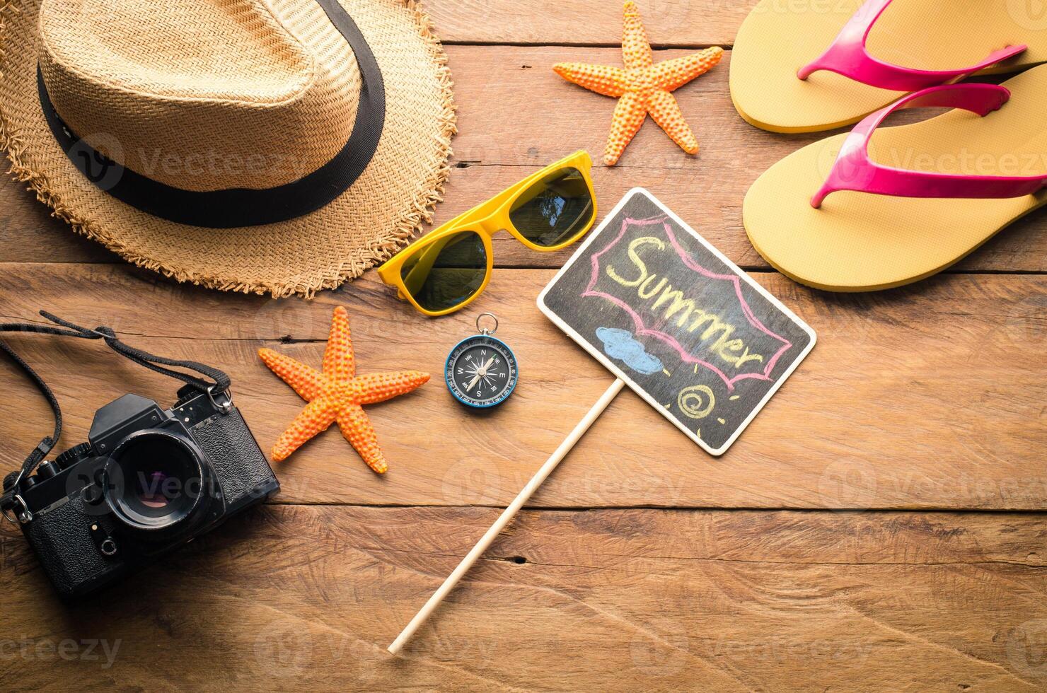 Meer Reise Zubehör ein Hut, Sonnenbrille, Kamera. platziert auf hölzern mit Wort Sommer- auf Tafel foto