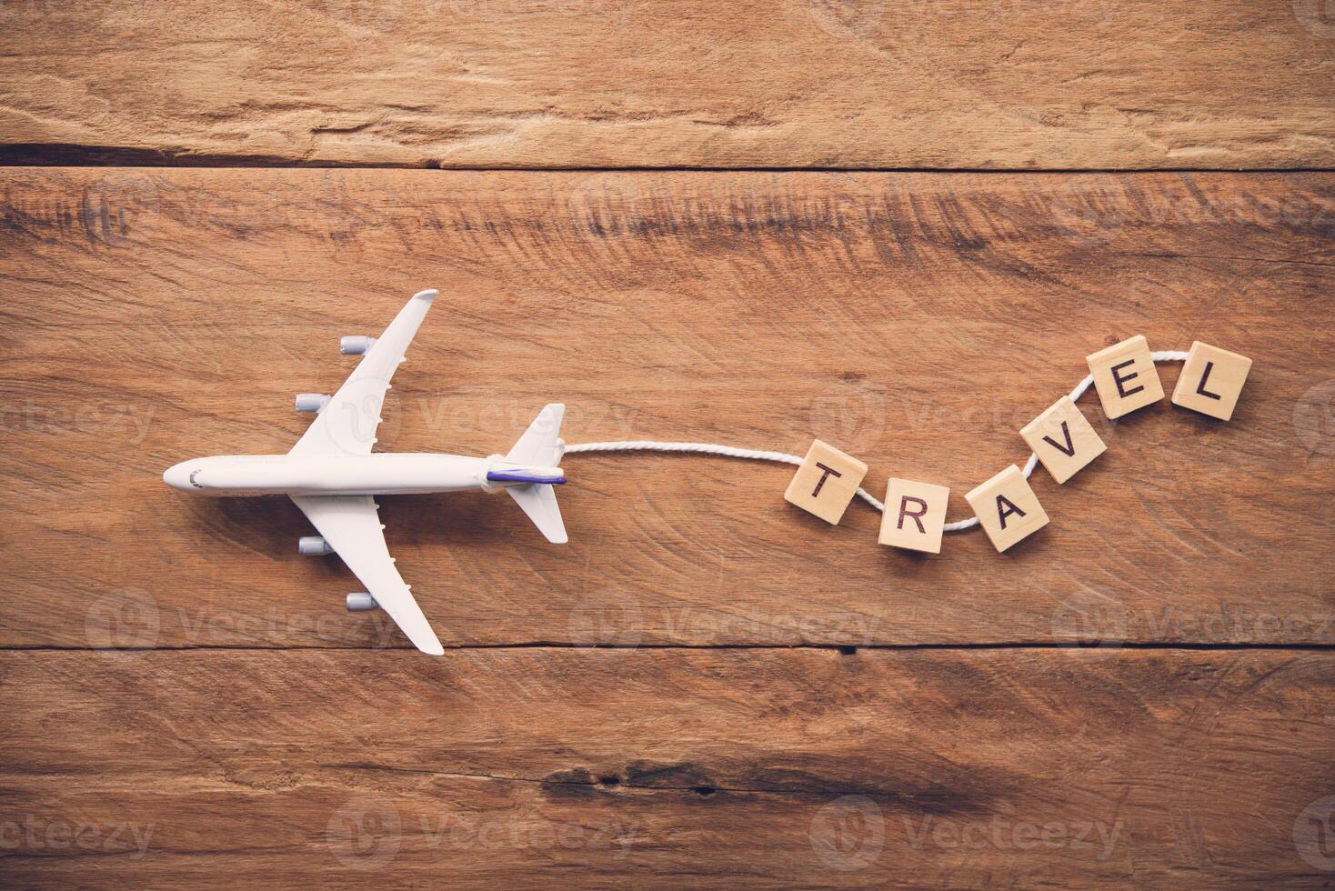 Flugzeug mit das Text Reise platziert auf ein hölzern Boden. Reise Ideen foto