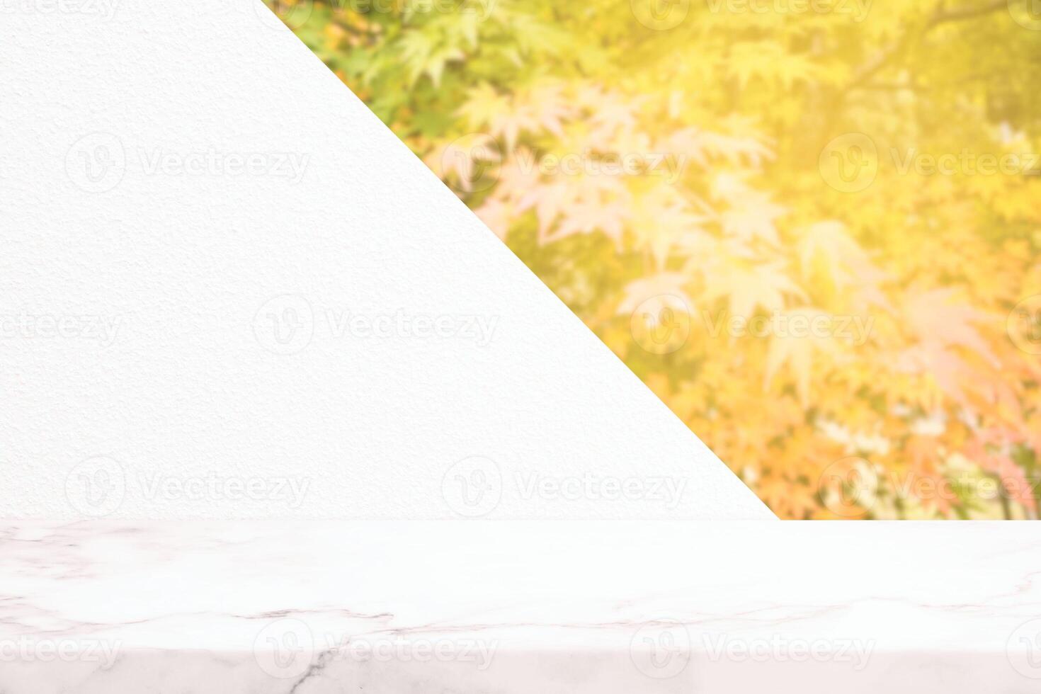 Weiß Marmor Tabelle mit Beton Mauer und verschwommen rot Ahorn Blätter im das Herbst Hintergrund mit Licht Leck, geeignet zum Produkt Präsentation Hintergrund, Anzeige, und spotten hoch. foto