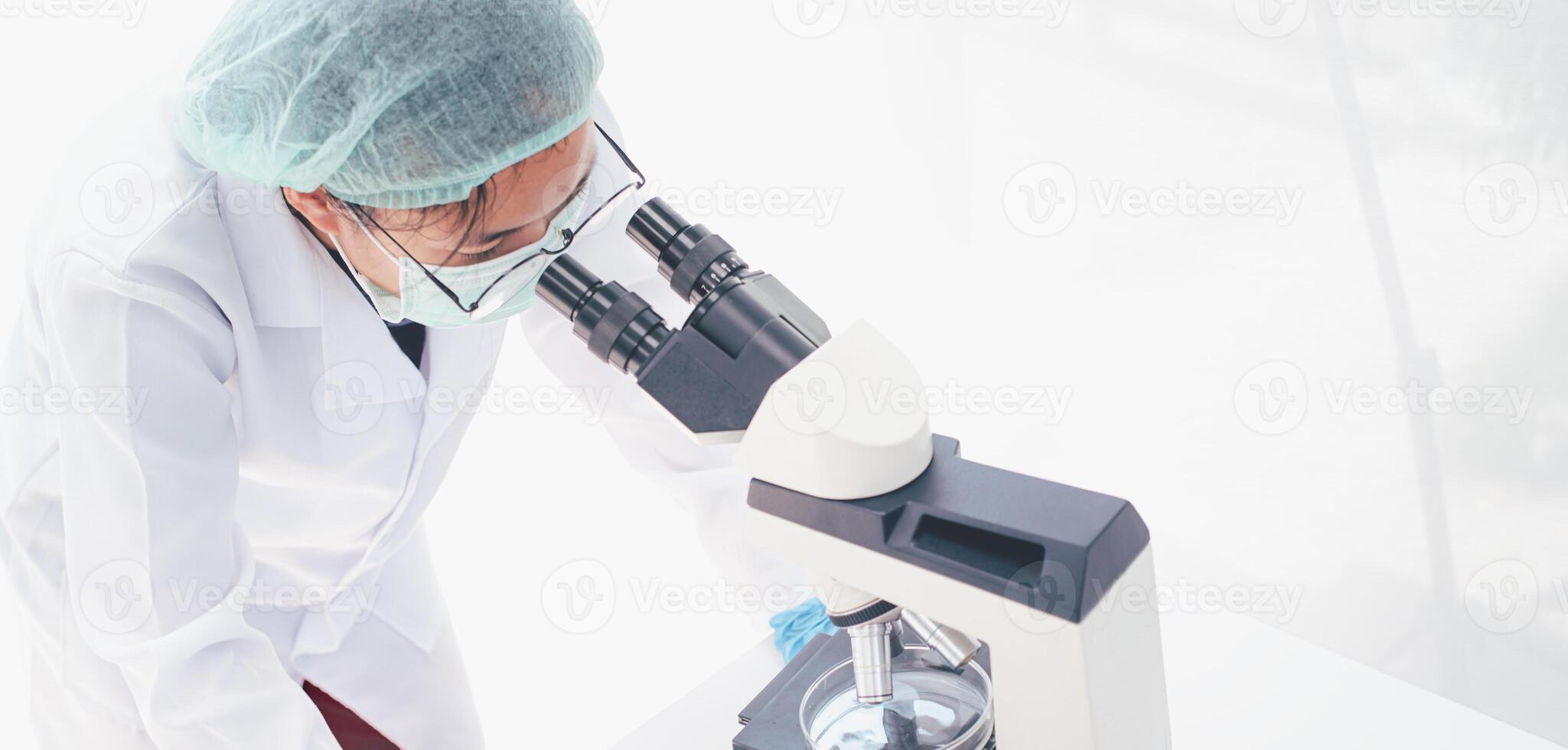 weiblich medizinisch Forscher suchen beim ein Mikroskop im ein medizinisch Labor. medizinisch Experimental- Konzept foto
