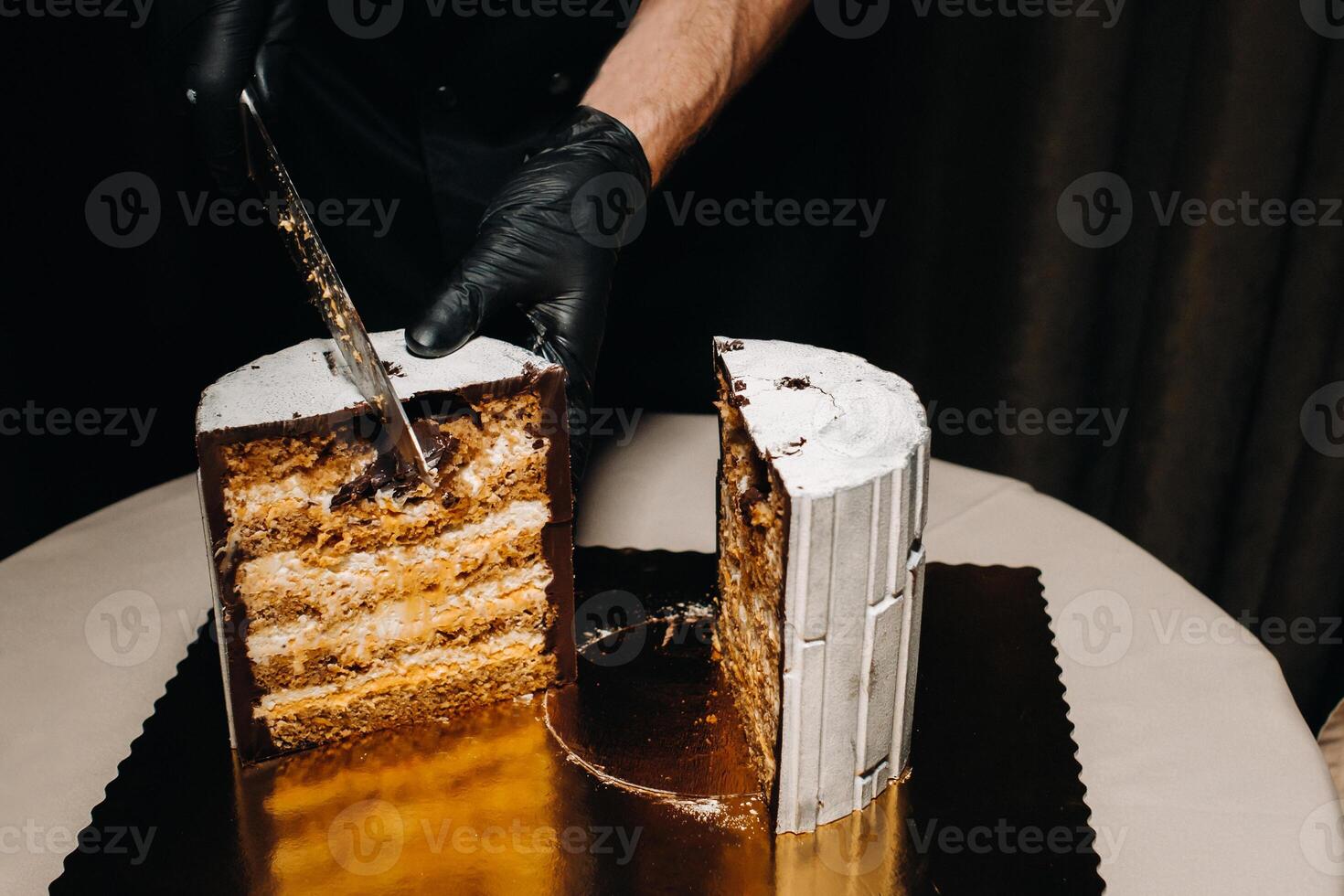 tolle Kuchen. ein schwarz behandschuht Koch ist Schneiden ein Schokolade Hochzeit Kuchen. das Hochzeit Kuchen ist köstlich Innerhalb auf ein schwarz Hintergrund.groß Kuchen im Weiß Schokolade. foto