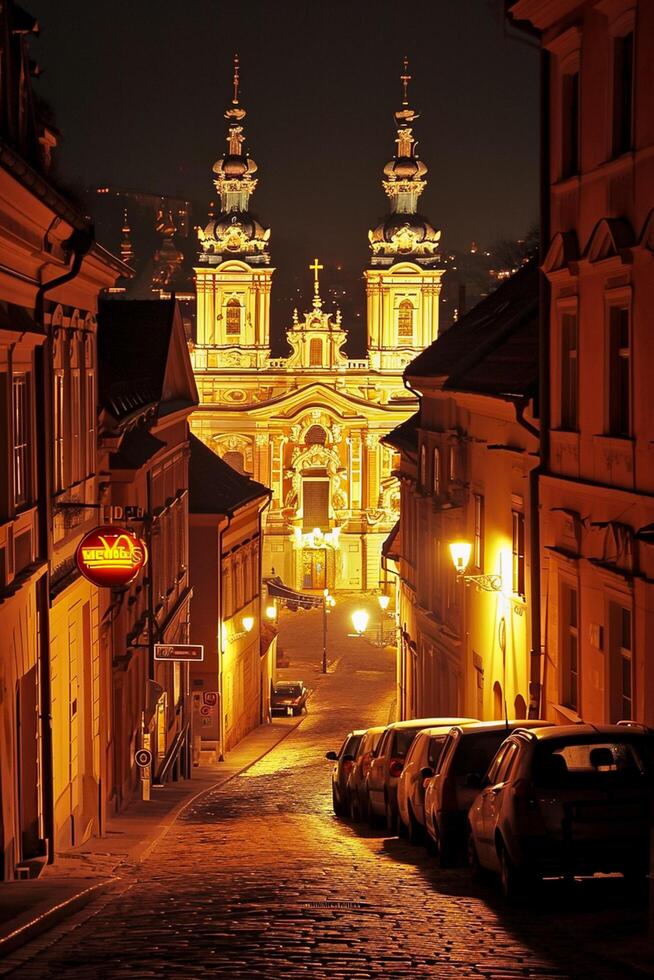 ai generiert Bild von schön beleuchtet Barock Stil Kirche, eingebettet zwischen klassisch architektonisch Gebäude auf Kopfsteinpflaster Straße beim Nacht ai generiert foto