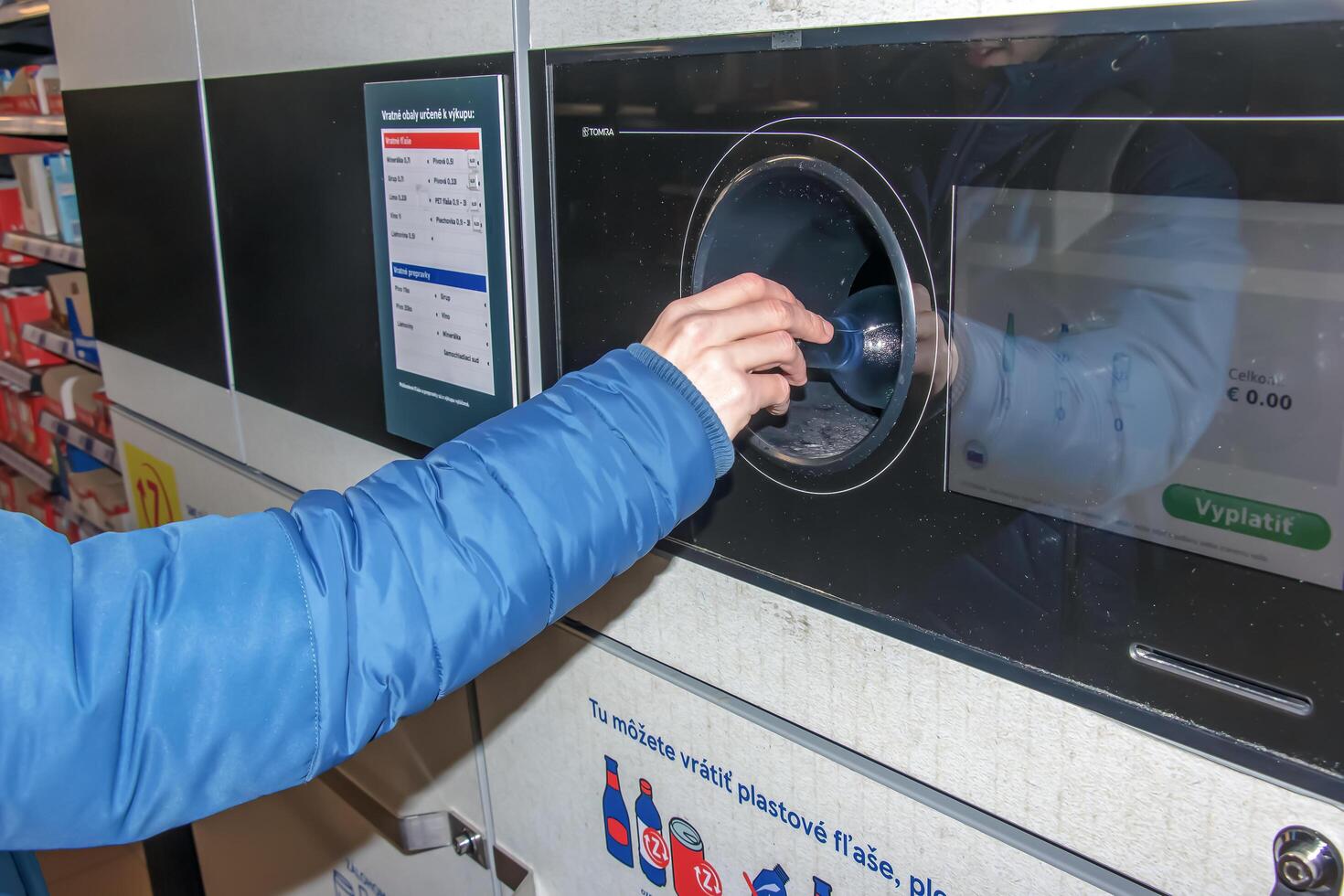 Nitra, Slowakei - - 16.01.2024 Nahansicht von ein des Mannes Hand Putten ein Flasche in ein Abfall Recycling Maschine. foto