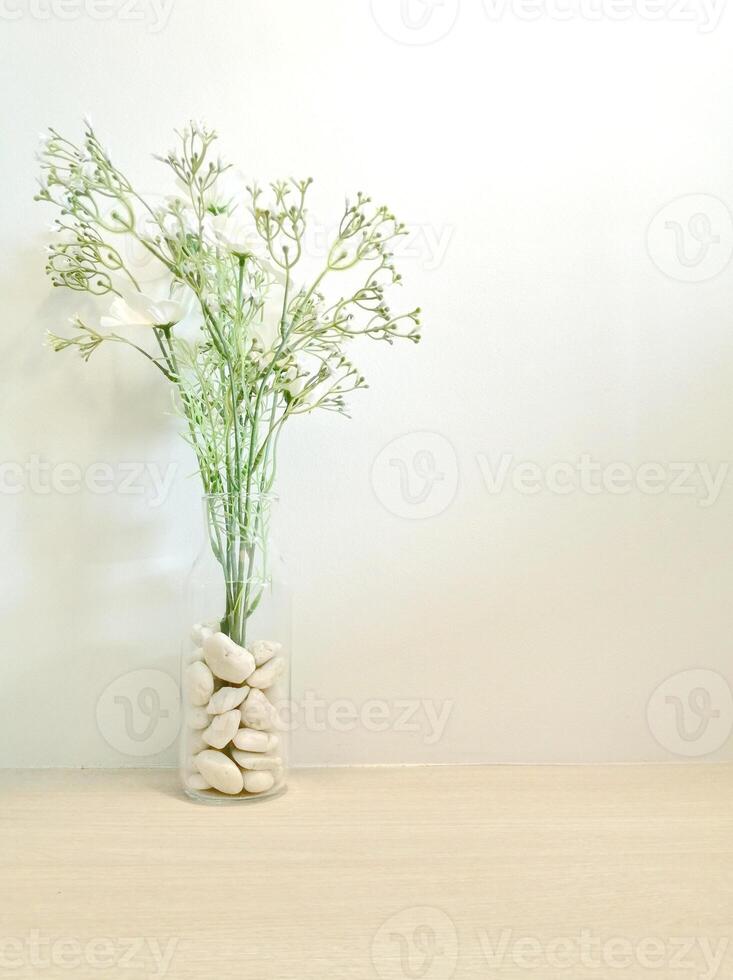 Weiß Steine im Glas Vase auf Holz Tabelle und Weiß Mauer Hintergrund foto