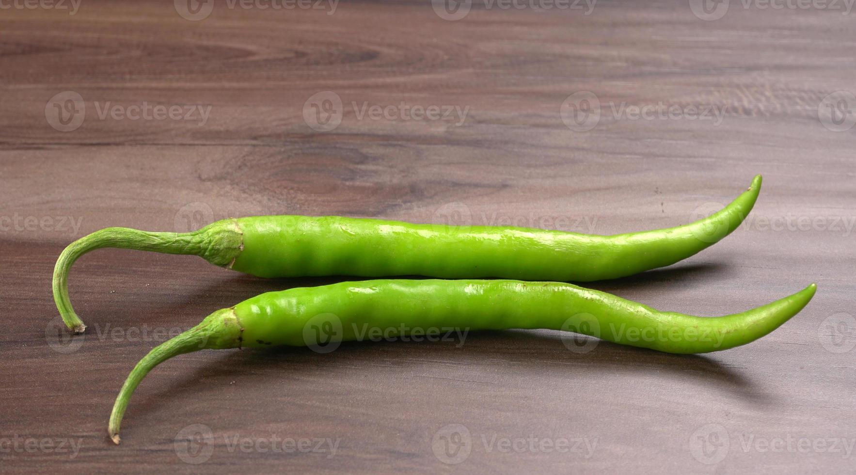 Frische lange indische grüne Chilis auf Holzhintergrund. foto