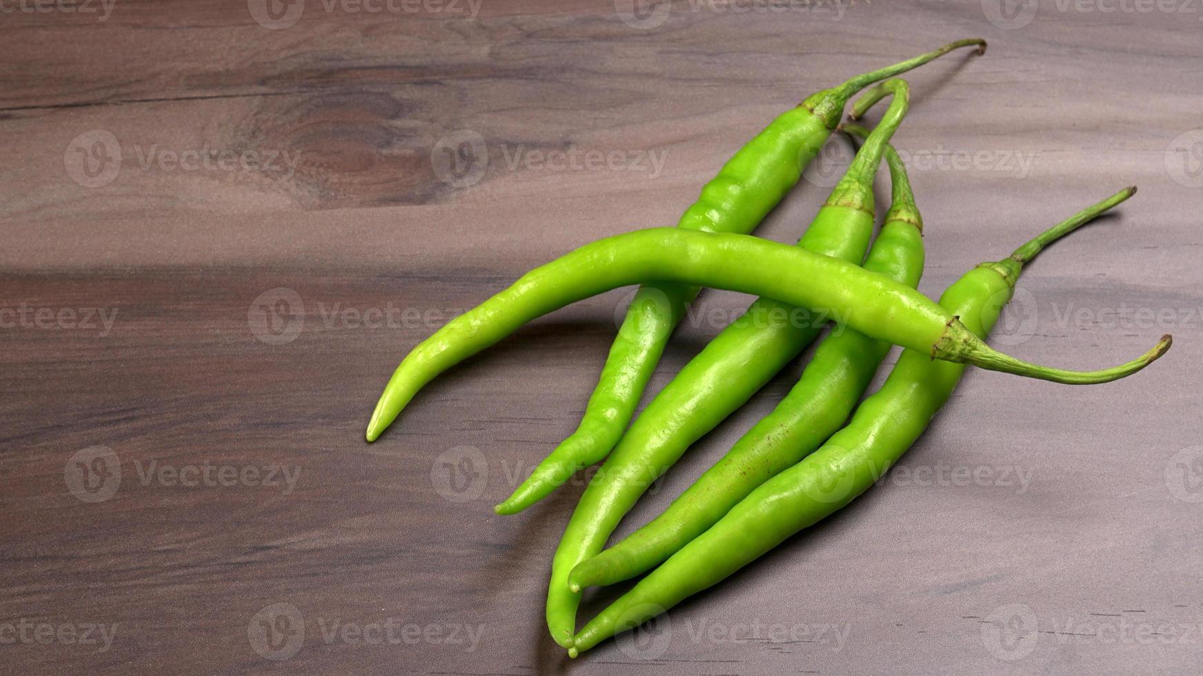 Frische lange indische grüne Chilis auf Holzhintergrund. foto