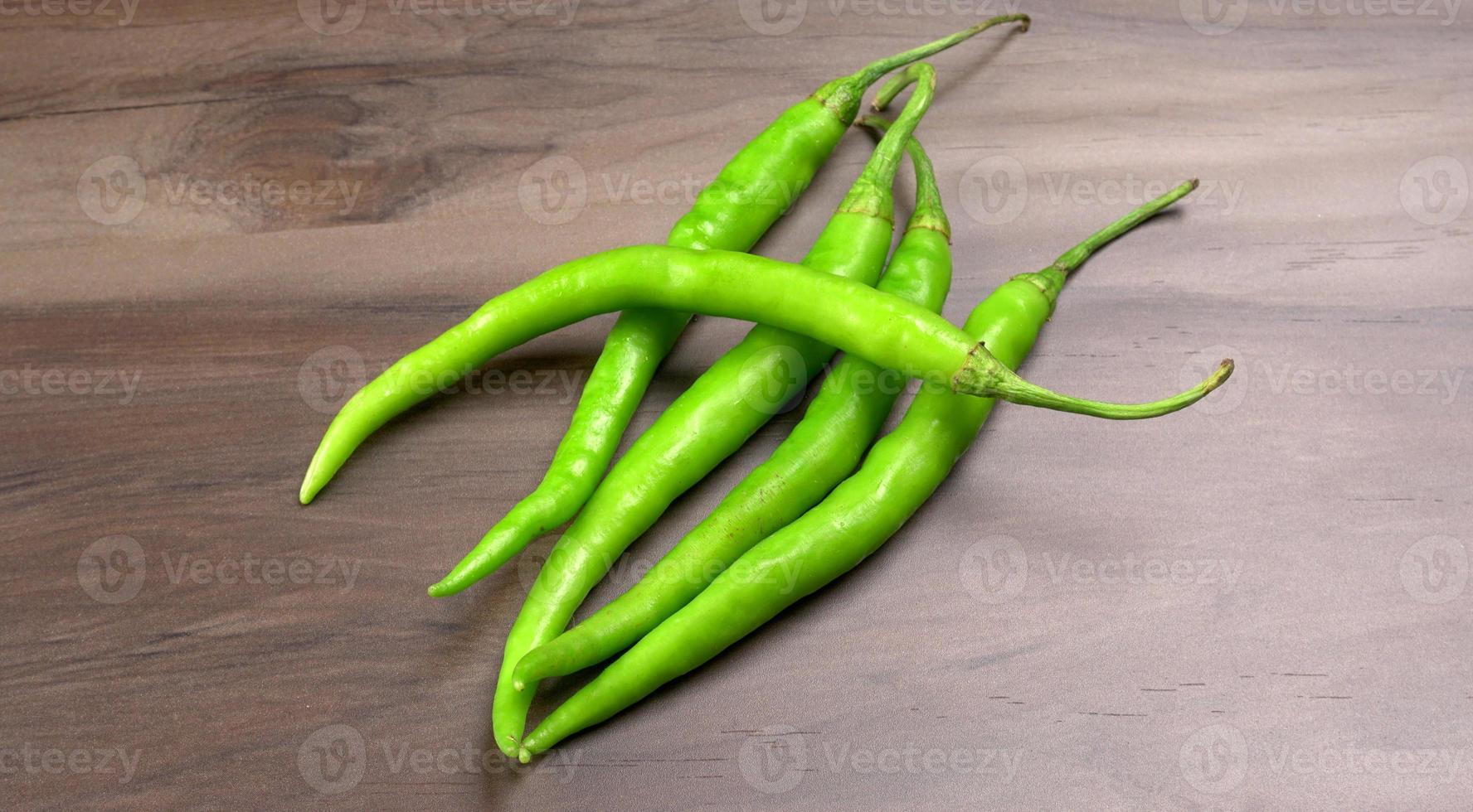 Frische lange indische grüne Chilis auf Holzhintergrund. foto