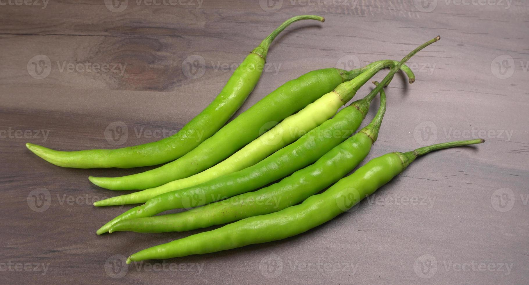 Frische lange indische grüne Chilis auf Holzhintergrund. foto