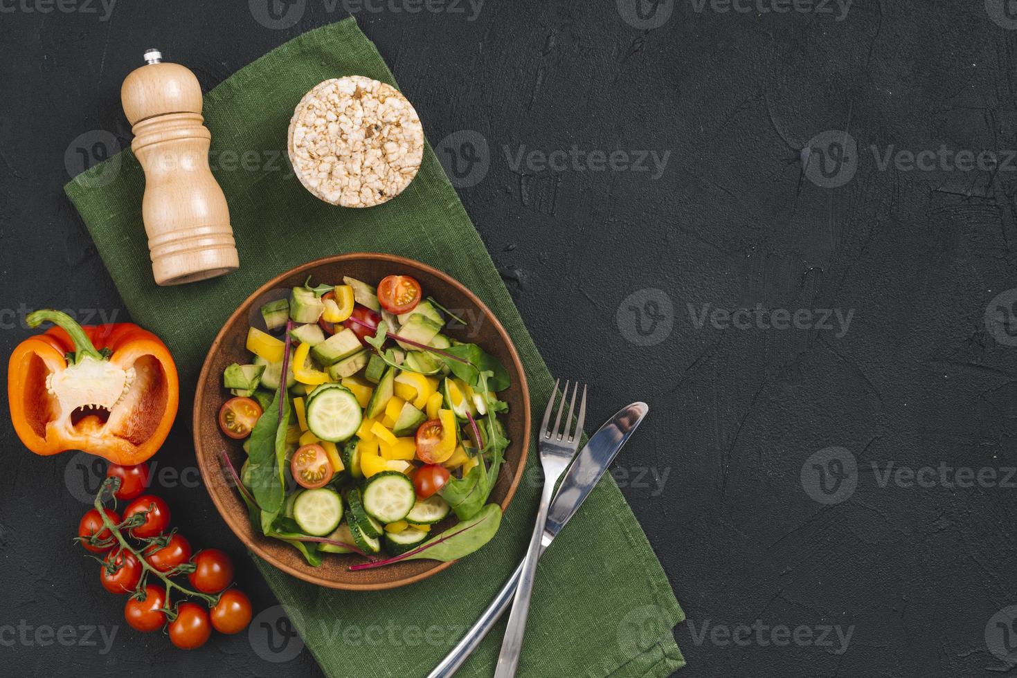Reis Puffkuchen Gemüse Salat Pfefferstreuer Serviette schwarzer Beton strukturierter Hintergrund foto