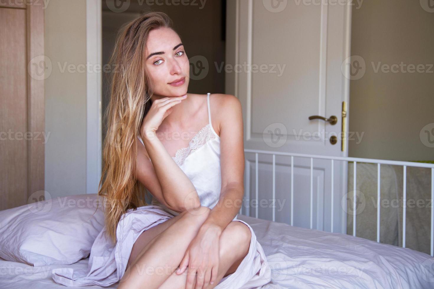 Perfekte sexy tan Lady Frau mit perfekter Haut, großen vollen Lippen posiert im Schlafzimmer, trägt sexy luxuriöse, stilvolle Dessous.l Dame liegt auf dem Bauch auf weißem Bett. foto