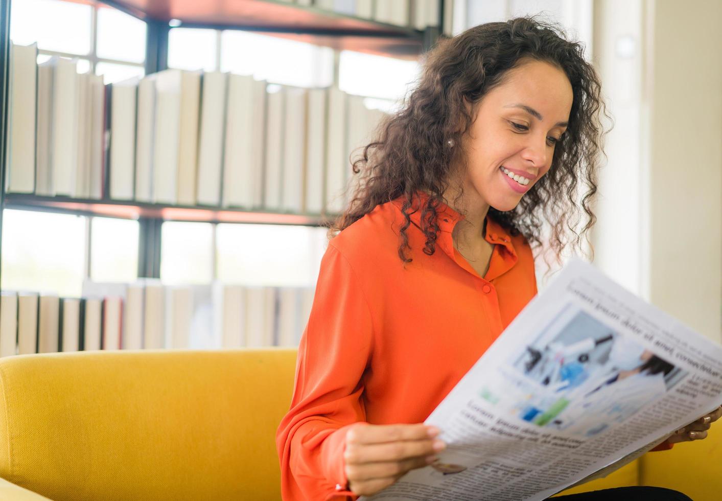 Lateinamerikanische Frau liest Zeitung auf dem Sofa foto