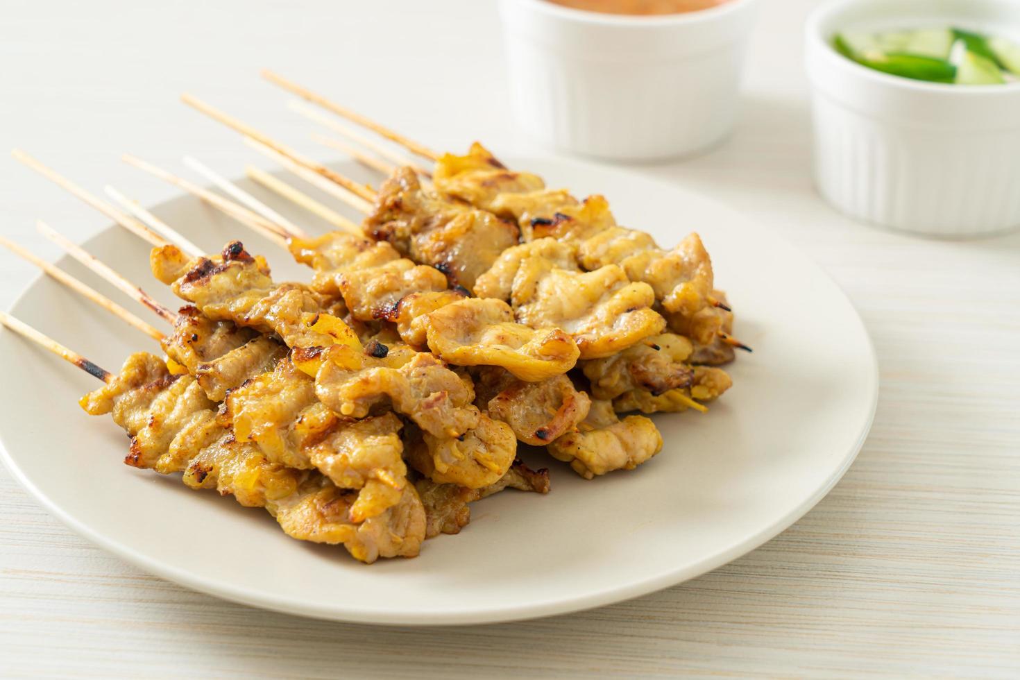 Schweine-Satay mit Erdnusssauce Gurkenscheiben und Zwiebeln in Essig foto