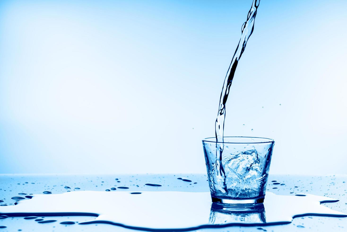 Wasser in Glas auf blauem Hintergrund gießen foto