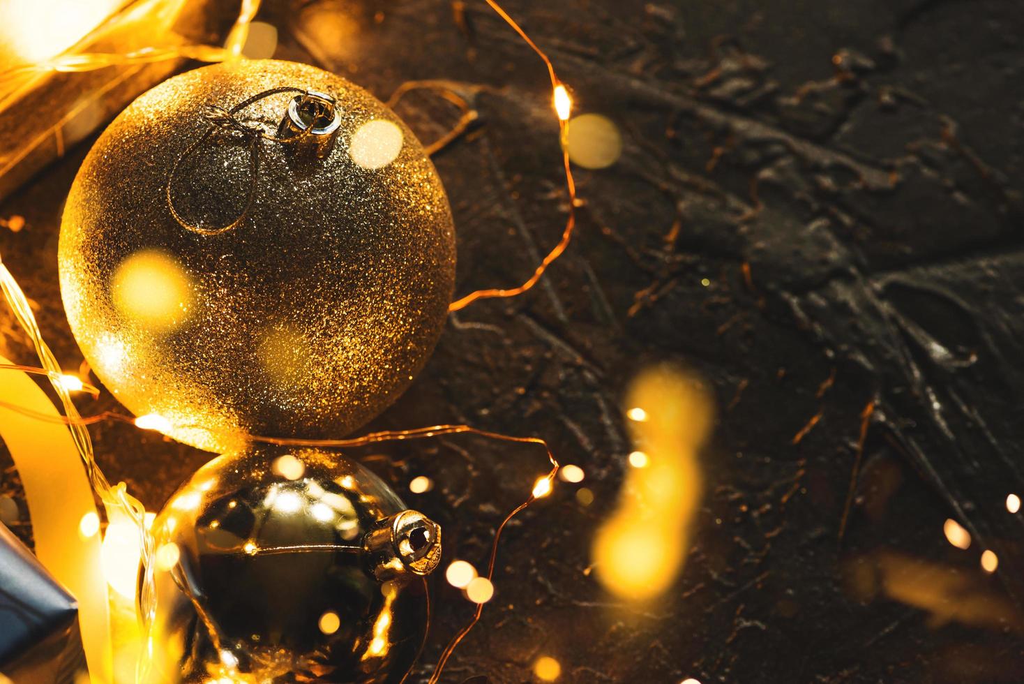 Weihnachtsdekorationskugeln auf abstraktem bokeh schwarzem Hintergrund mit Kopienraum und dekorativen LED-Leuchten. frohe weihnachten und neues jahr. foto