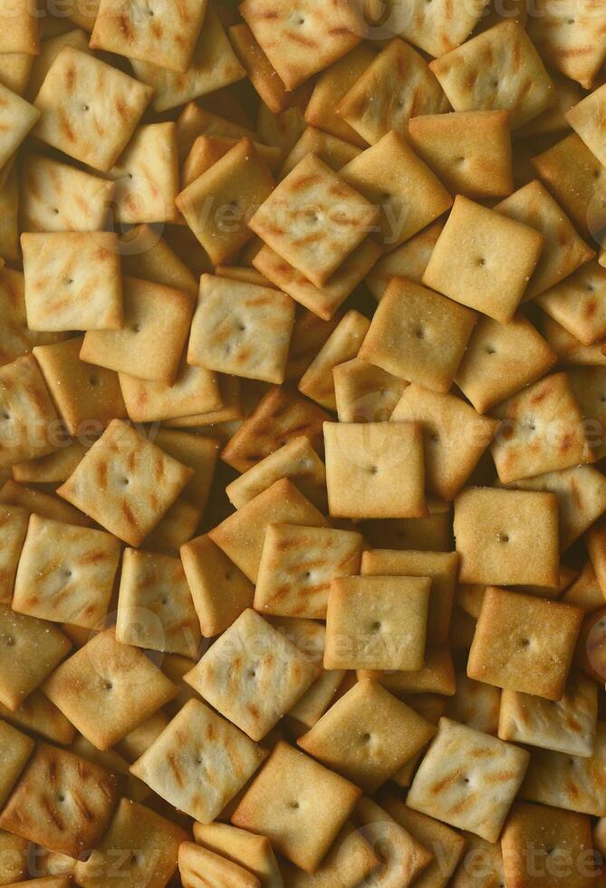 Viele kleine Kekse sind quadratisch. ein Muster eines gelben Salzcrackers. Hintergrundbild mit Salzgebäck foto