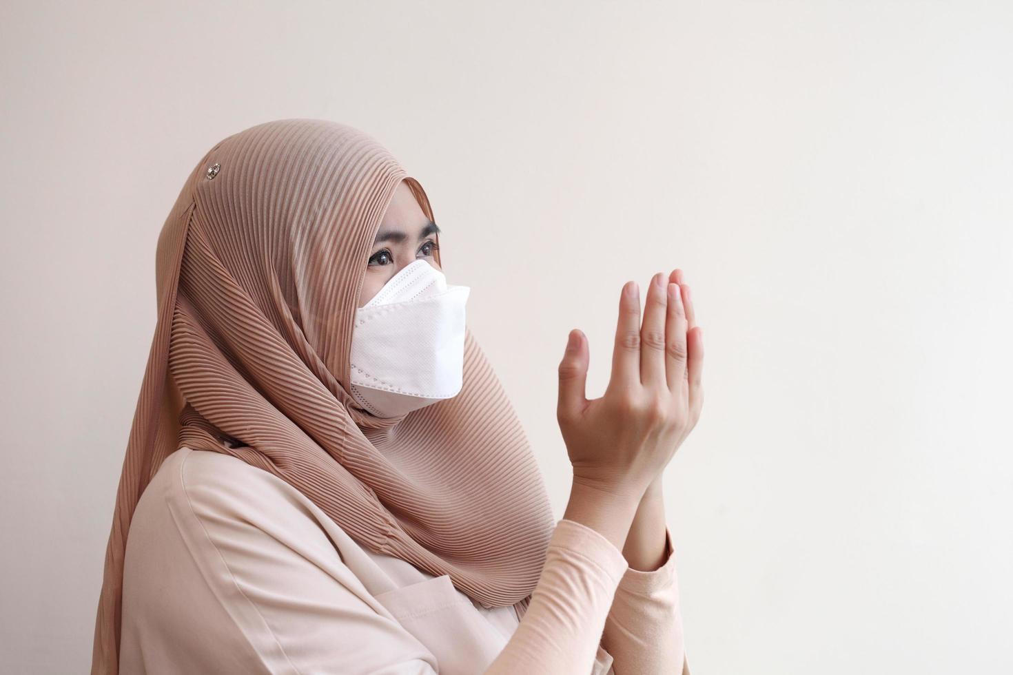 muslimisches Mädchen, das eine chirurgische Maske trägt und während der Arbeit von zu Hause aus betet. Covid-19-Coronavirus-Konzept. foto