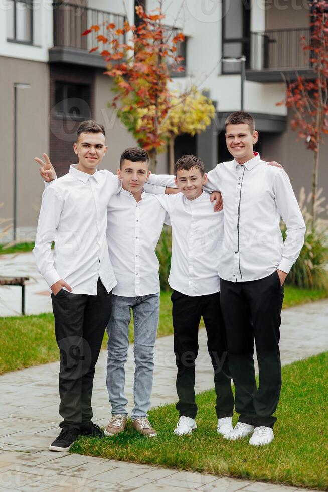 Gruppe von lächelnd und glücklich Teenager freunde tragen beiläufig Kleider Ausgaben Zeit zusammen, posieren und reden mit jeder andere in der Nähe von Hochschule Gebäude auf Herbst Tag. foto