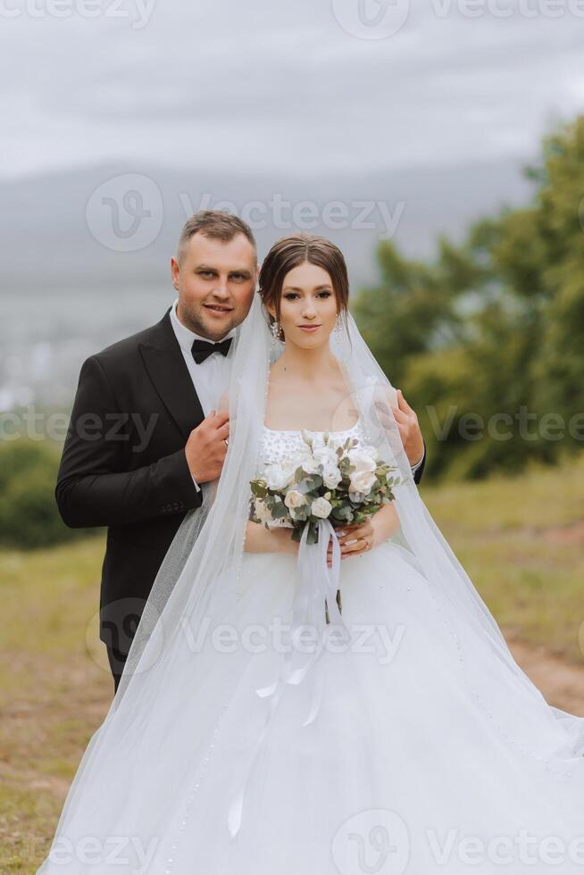 Hochzeit. Liebe und Paar im Garten zum Hochzeit. Feier von Zeremonie und Engagement. speichern das Datum. Vertrauen das Bräutigam umarmt das Braut im das Berge auf das Hintergrund von das Wald foto