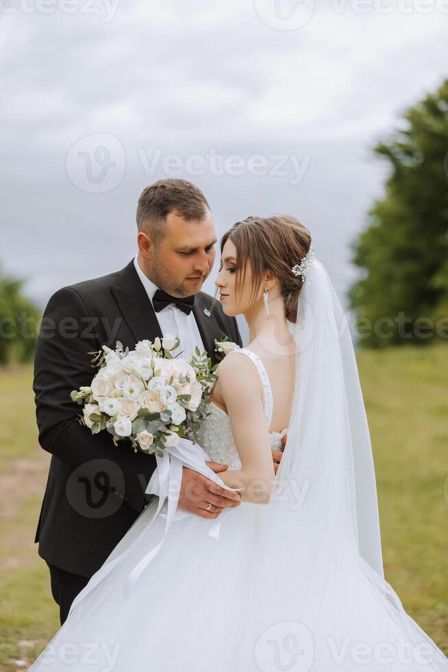 Hochzeit. Liebe und Paar im Garten zum Hochzeit. Feier von Zeremonie und Engagement. speichern das Datum. Vertrauen das Bräutigam umarmt das Braut im das Berge auf das Hintergrund von das Wald foto