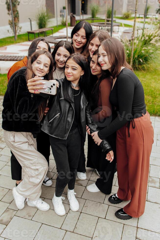 freunde nehmen ein groß Gruppe Selfie lächelnd beim das Kamera - - Lachen jung Menschen Stehen draußen und haben Spaß - - Porträt von heiter Schulkinder draußen Schule - - Mensch Ressourcen Konzept foto