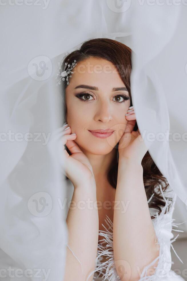 ein schön Brünette Braut mit ein Tiara im ihr Haar ist bekommen bereit zum das Hochzeit im ein schön Kleid im Boudoir Stil. Nahansicht Hochzeit Porträt, Foto. foto