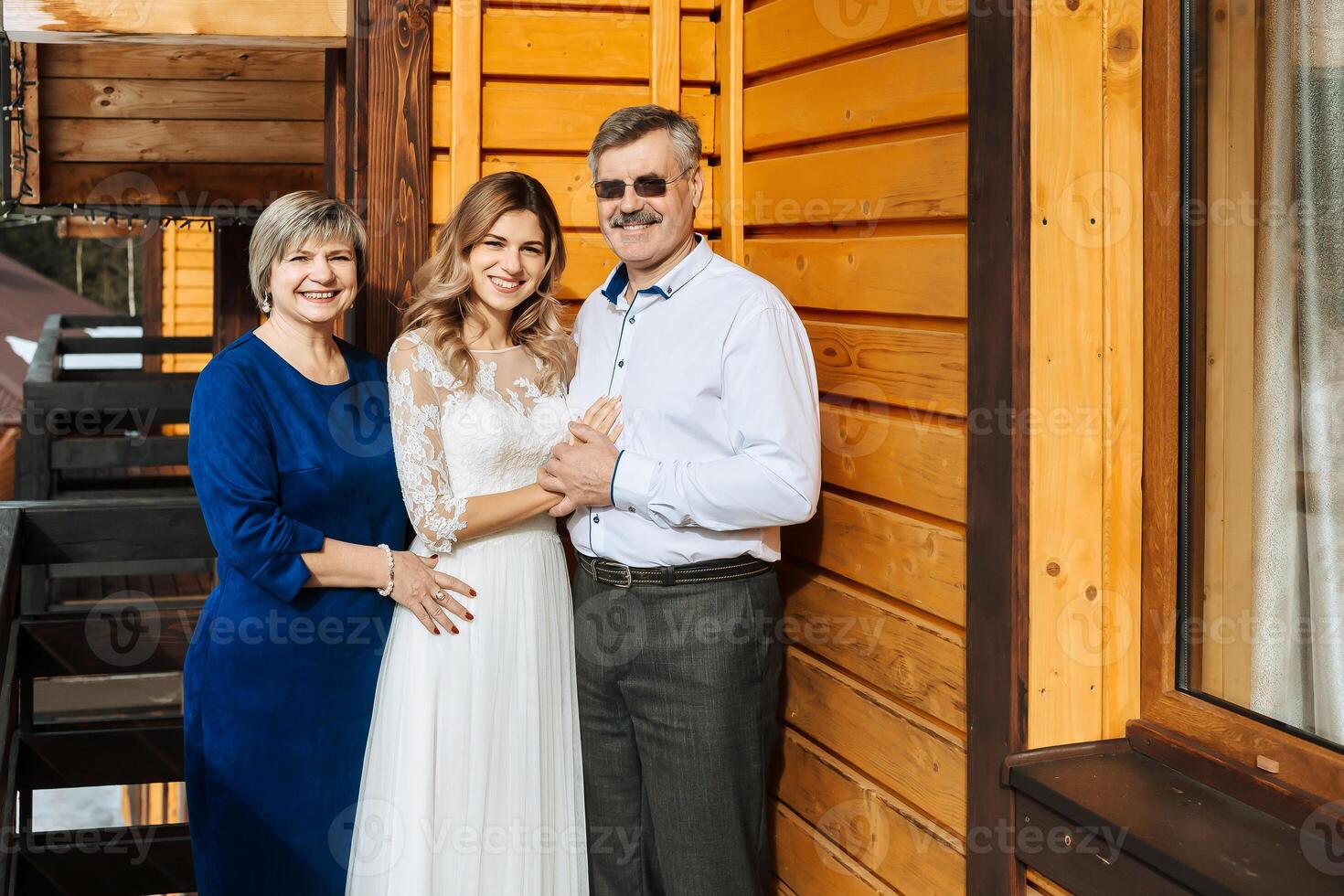 glücklich Eltern jubeln zum ihr Tochter, Wer werden bald erhalten verheiratet. berühren Momente beim das Hochzeit. Mama und Papa Umarmung Tochter Braut. Porträt von Eltern mit Braut foto