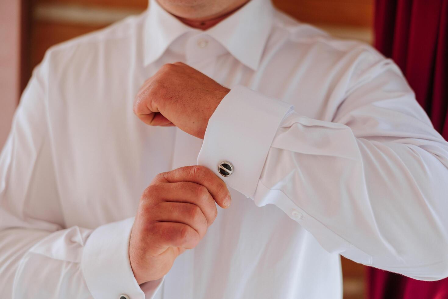 gut aussehend Geschäft Mann Knöpfen Hemd Ärmel beim heim. das Bräutigam ist vorbereiten zum das Hochzeit. Nahansicht Foto. foto