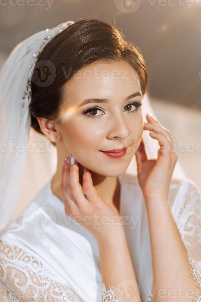 das Braut im ein Seide passen mit ein Schleier posiert im ihr Zimmer. Morgen von das Braut. Vorbereitung. Hochzeit Fotografie foto