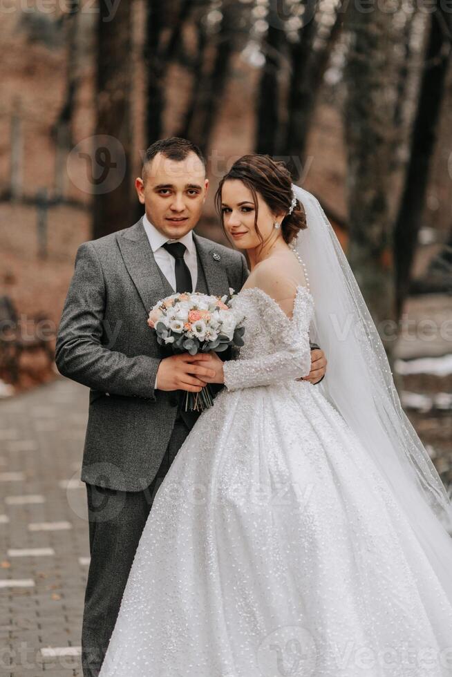 Porträt. das Braut und Bräutigam sind Stehen, halten ein Strauß, posieren im das Wald. ein gehen im das Wald. Winter Hochzeit foto