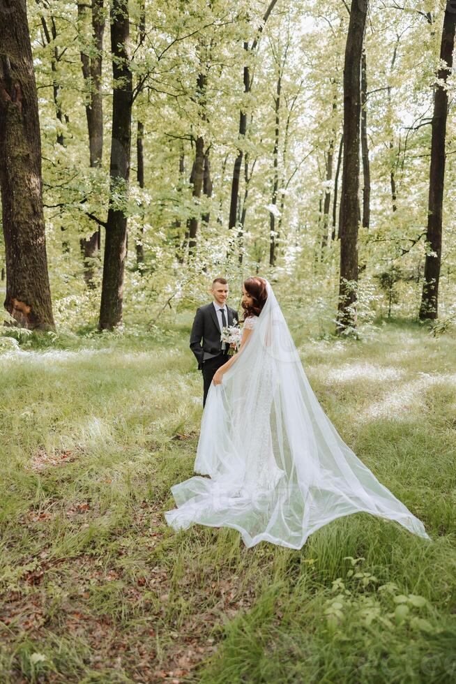 Hochzeit. Liebe und Paar im Garten zum Hochzeit. feiern das Zeremonie und Engagement. speichern das Datum. Vertrauen. das Bräutigam umarmt das Braut gegen das Hintergrund von ein Grün Hintergrund. Paar im Liebe foto