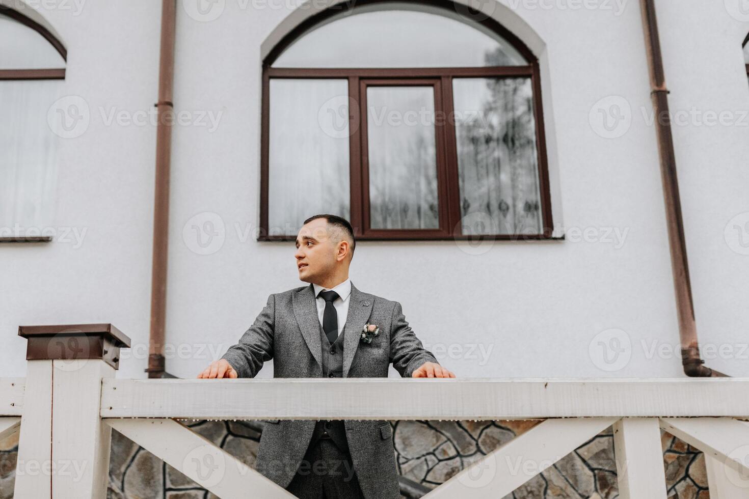 Porträt. das Bräutigam posiert gegen das Hintergrund von das Hotel. Geschäft Stil. Winter Hochzeit foto