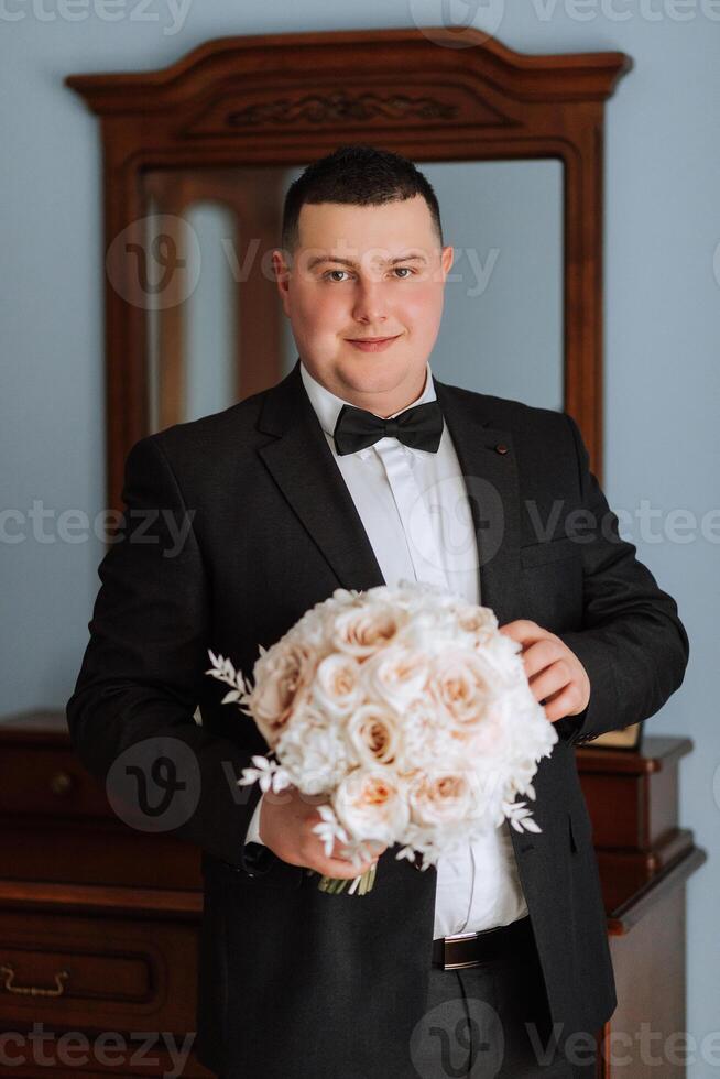 stilvoll Porträt von das Bräutigam mit ein Strauß von Blumen. ein Mann ist vorbereiten zum ein Hochzeit Zeremonie im das Morgen. Bräutigam Morgen. Vorbereitung zum das Bräutigam Morgen. jung und gut aussehend Bräutigam. foto