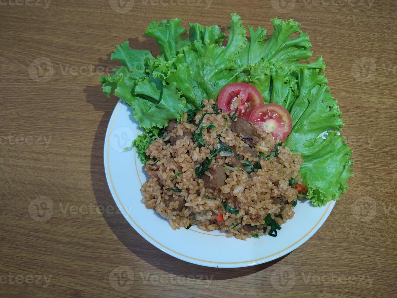 köstlich indonesisch gebraten Reis nasi goreng mit viele von Kopfsalat, Senf Grüns und Tomaten serviert auf ein Weiß Teller foto