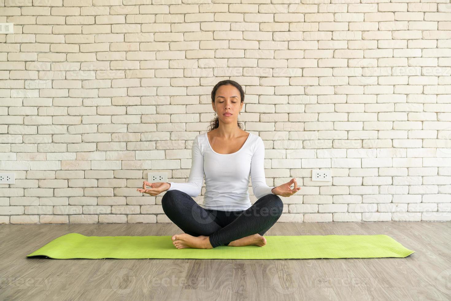 lateinische frau, die yoga auf matte praktiziert foto