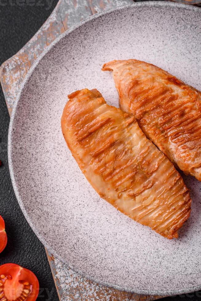 Köstliches frisch gegrilltes Hähnchenfilet mit Gewürzen und Kräutern auf dunklem Betonhintergrund foto