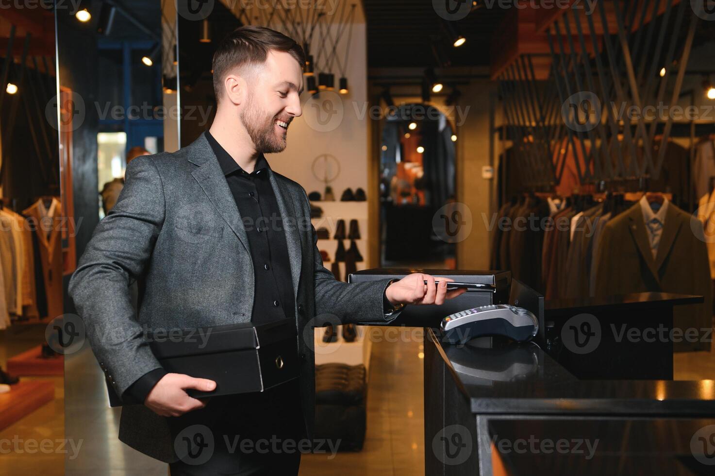 glücklich Käufer halten Kisten mit Neu Kleider oder Schuhe und bezahlen durch Telefon foto