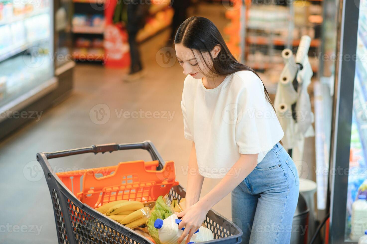 jung lächelnd glücklich Frau 20er Jahre tragen beiläufig Kleider Einkaufen beim Supermarkt Geschäft Kaufen wählen Milch foto