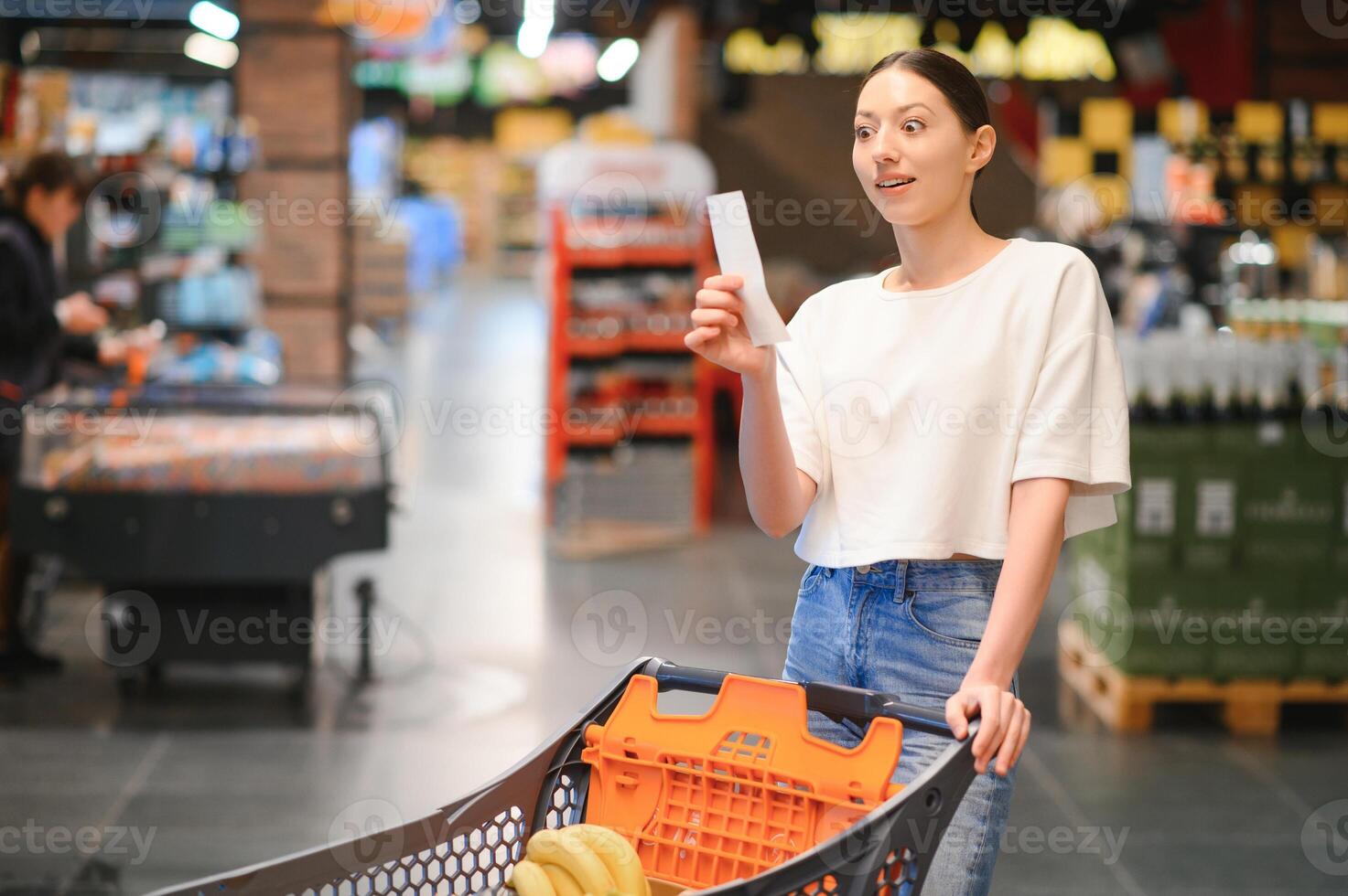 Frau beim Supermarkt halten ein voll Einkaufen Wagen und ein Einkaufen aufführen foto