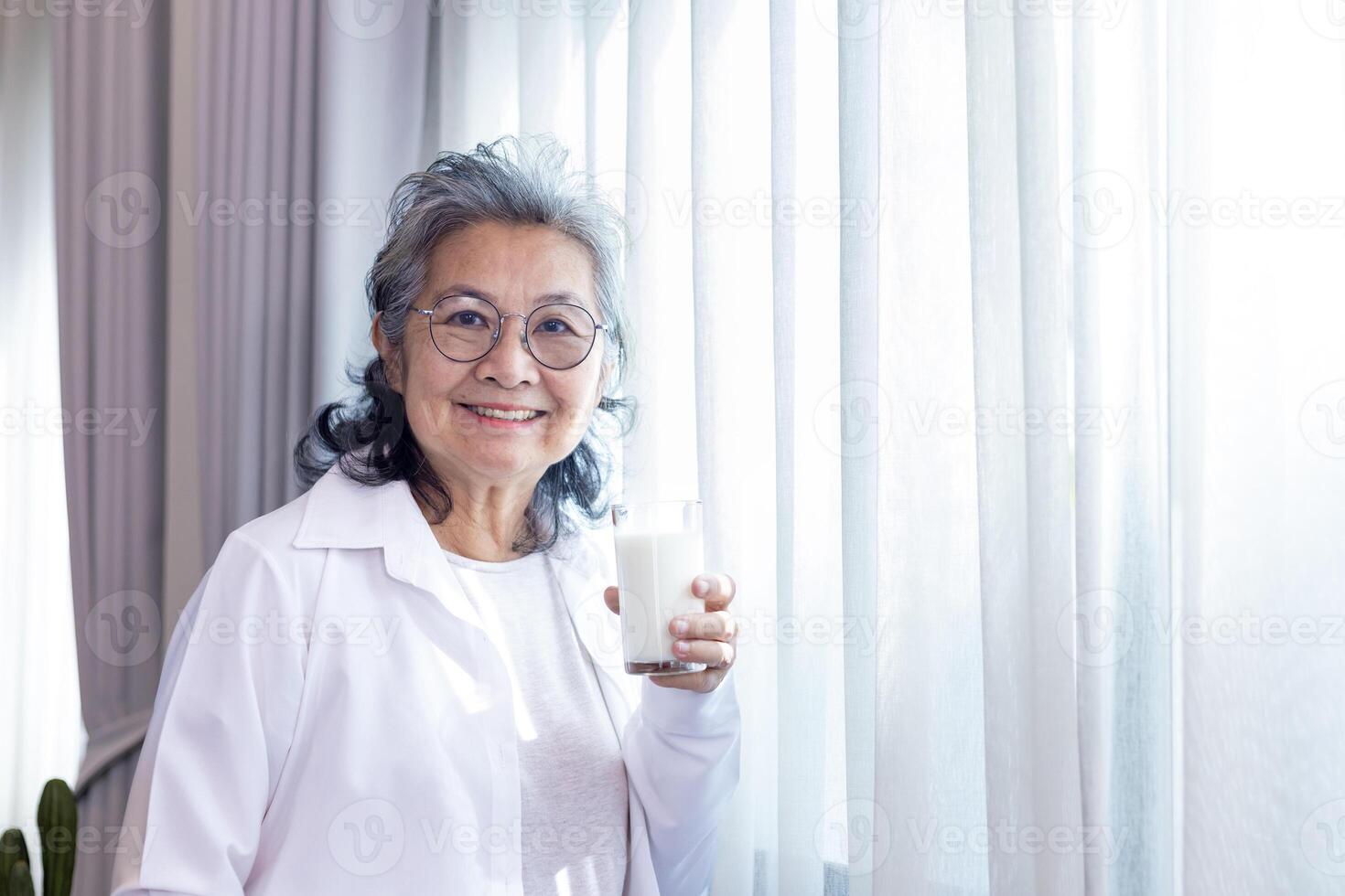 Senior asiatisch Dame Trinken Glas von Milch während Stehen durch das Fenster mit Kopieren Raum zum Kalzium erhöhen und gesund Molkerei Produkt Verbrauch Konzept foto