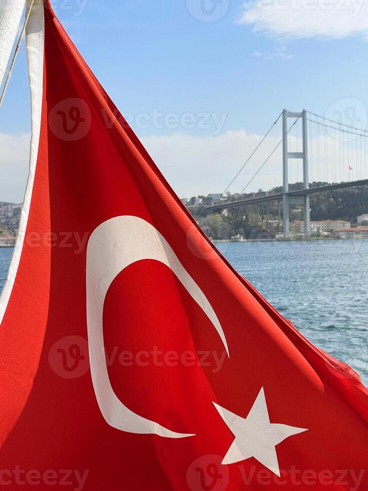 Türkisch Flagge flattern im das Wind mit Istanbul und das golden Horn Brücke im das Hintergrund, Truthahn foto