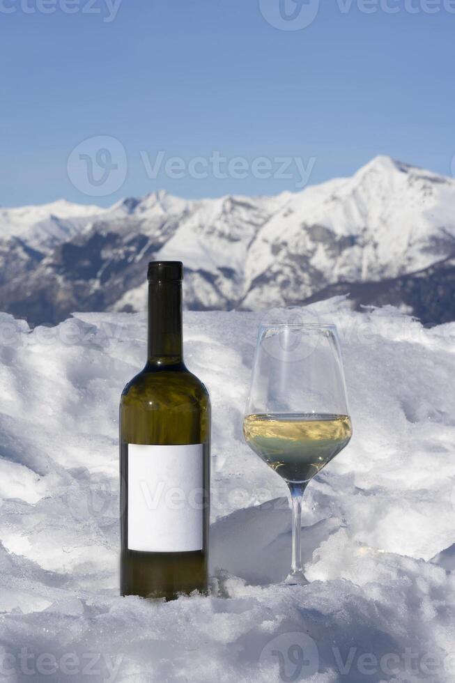 ein Flasche von Wein und ein Glas von Wein auf ein schneebedeckt Berg foto