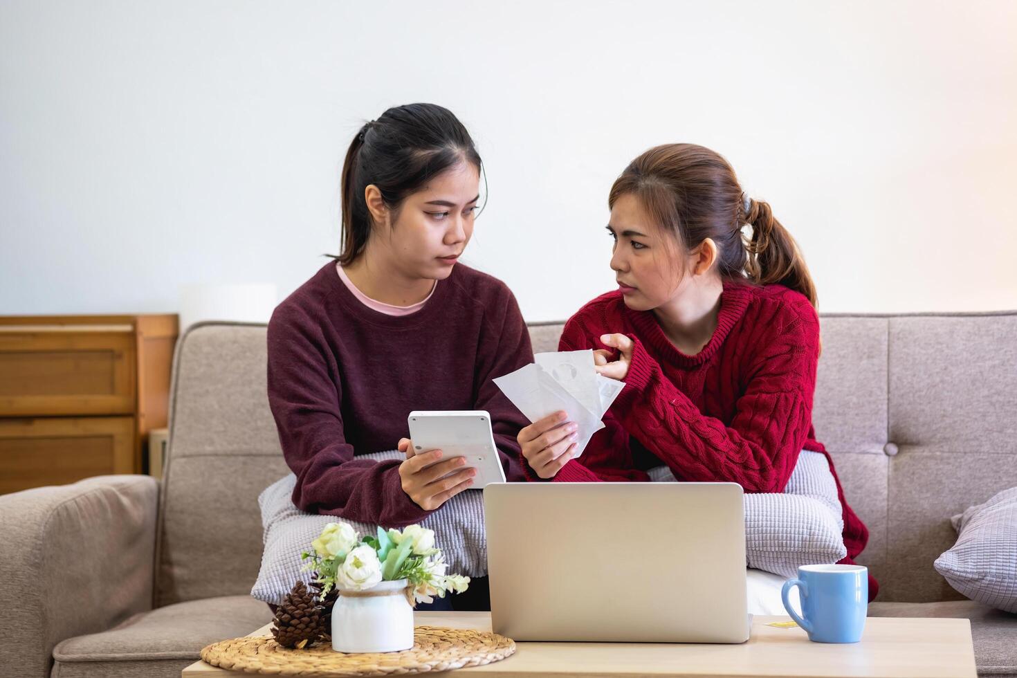 ein jung asiatisch Frau sitzt auf ein Sofa im ihr heim, Gefühl besorgt und frustriert Über ihr monatlich Kosten. verschiedene Nützlichkeit Rechnungen. foto