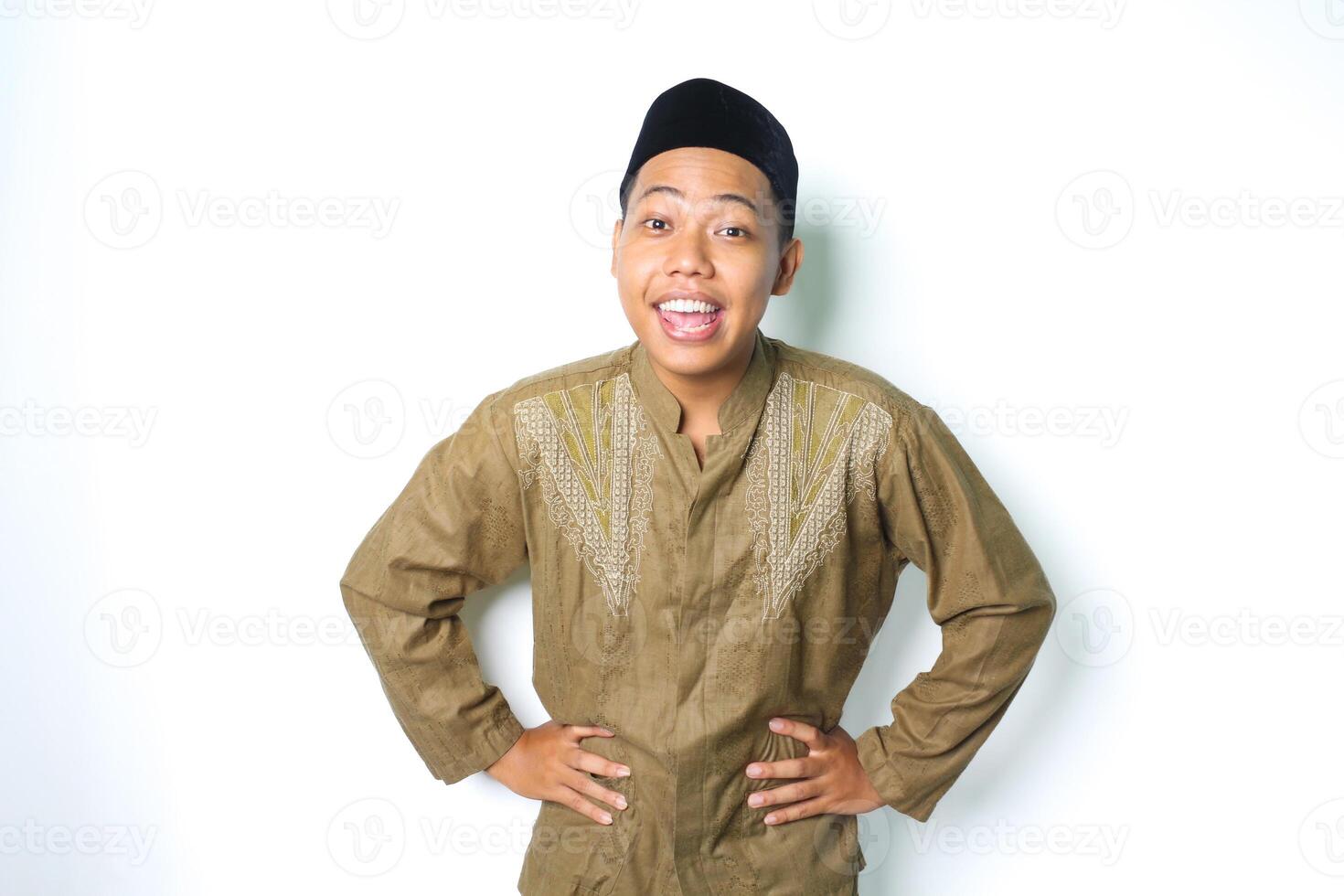 aufgeregt asiatisch Muslim Mann tragen islamisch Kleid suchen beim Kamera mit Hände auf Taille isoliert auf Weiß Hintergrund foto