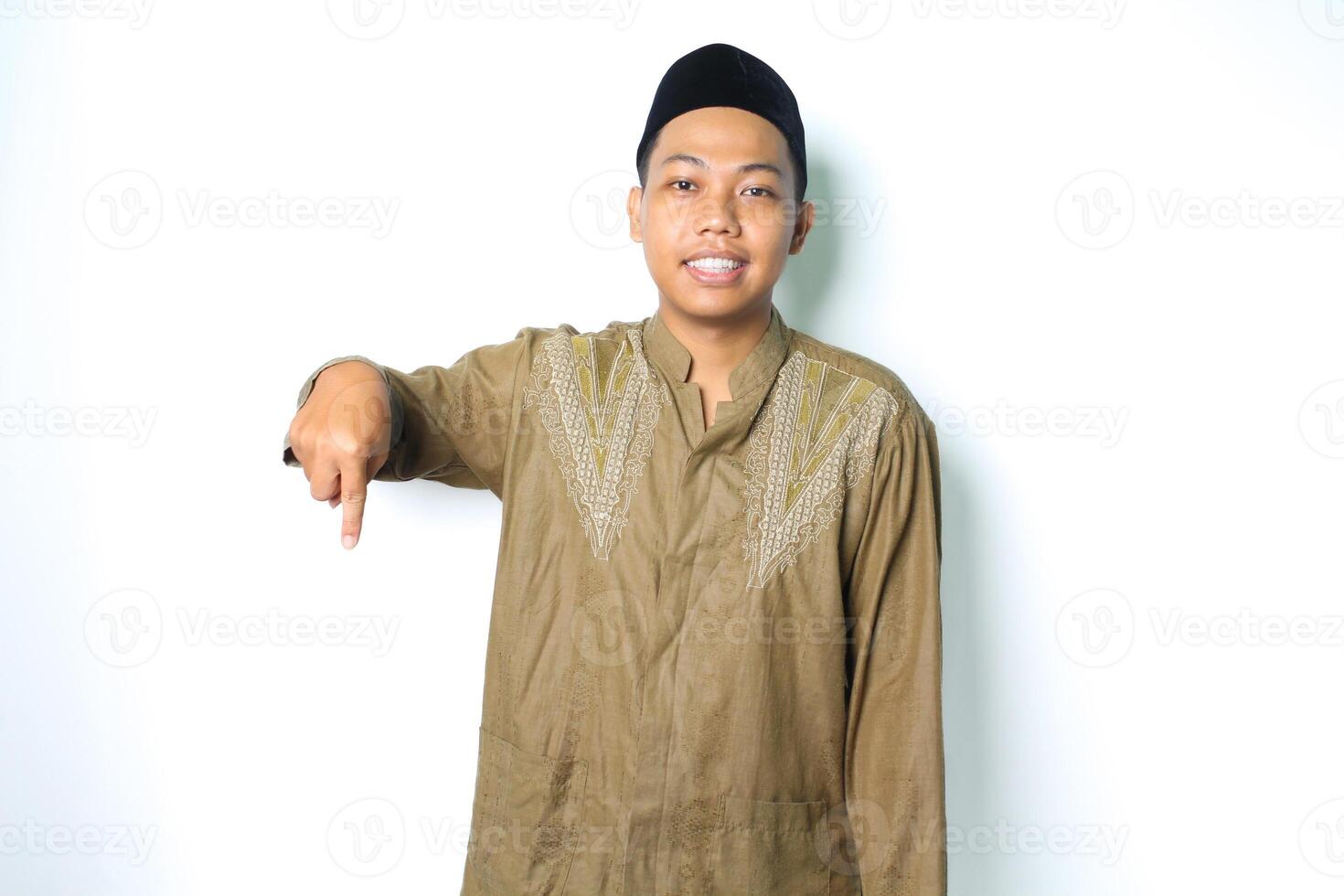 asiatisch Muslim Mann zeigen Nieder und lächelnd beim Kamera tragen islamisch Kleid isoliert auf Weiß Hintergrund foto