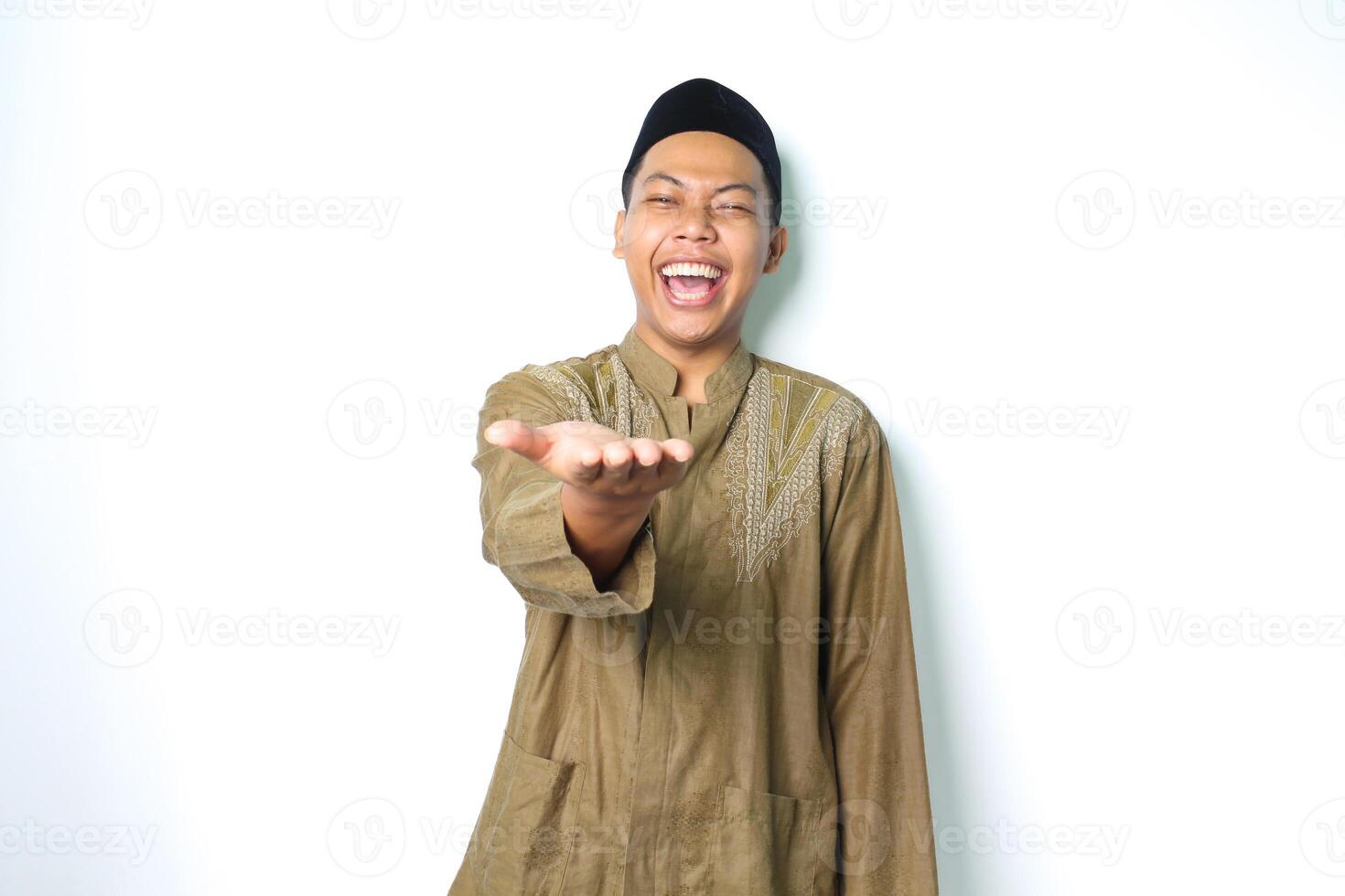 begeistert asiatisch Moslem Mann tragen islamisch Kleid erziehen Palme beim Kamera zu präsentieren mit Lachen Ausdruck isoliert auf weiß Hintergrund foto