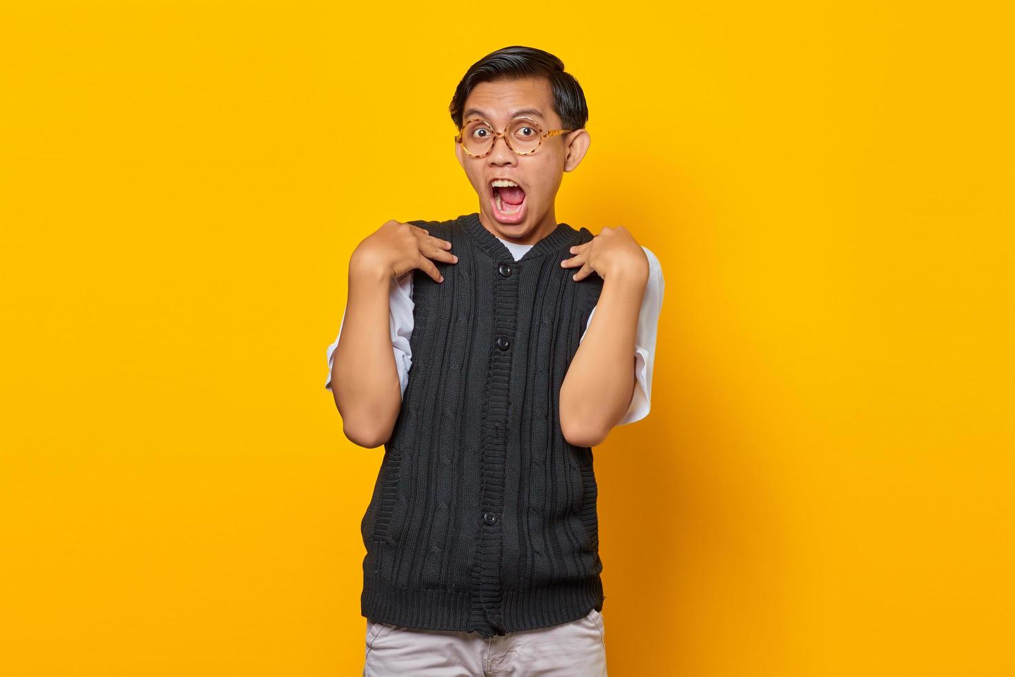 Porträt eines überraschten asiatischen Mannes mit offenem Mund über gelbem Hintergrund foto