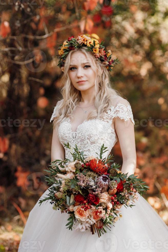 blondes Mädchen in einem Hochzeitskleid im Herbstwald foto